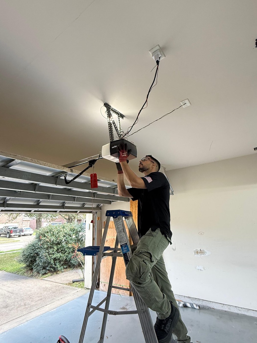 Technician working on a garage door opener mounted to the ceiling